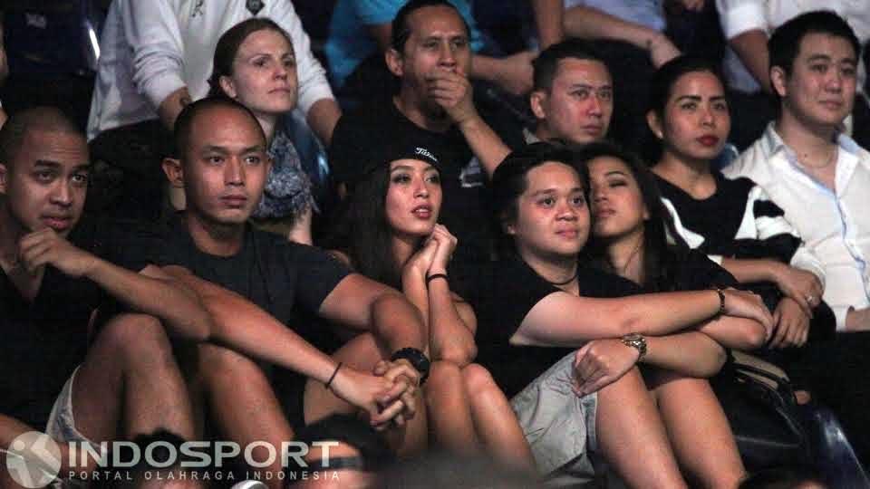 Wanita cantik bertopi menyaksikan dengan serius laga One Championship.